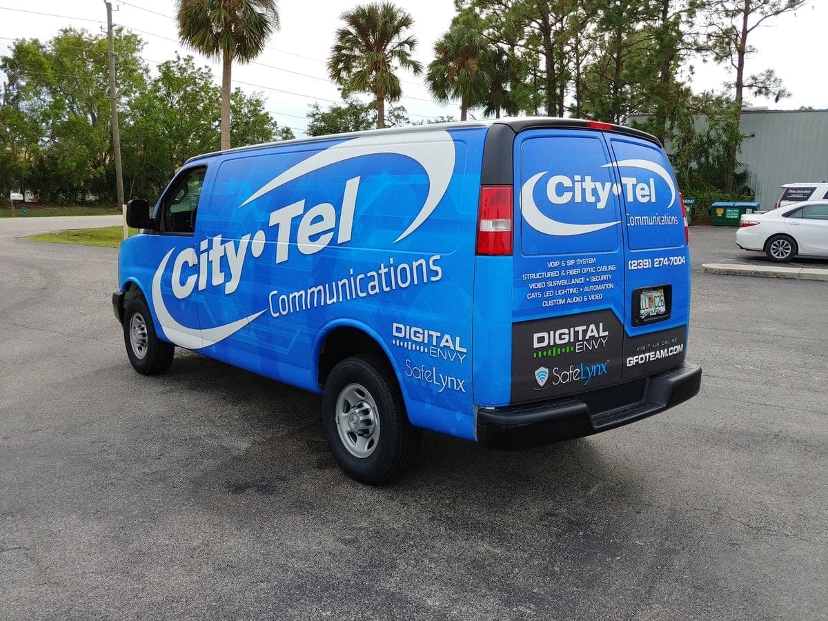Blue cargo van wrap for City-Tel Communications with a white swoosh logo, rear quarter view.
